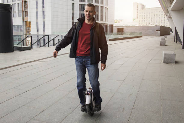 Casual man riding on one wheel electronic monocycle in the city. Middle aged man riding on one wheel electronic device in the city. Male rider on one foot doing trick. Modern technologies for transportation. Gyroboard as a personal eco transport hoverboard stock pictures, royalty-free photos & images