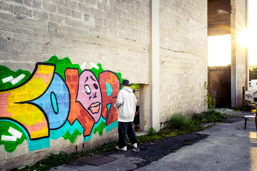 Young Man Doing Graffiti on the Wall of an Abandoned Building