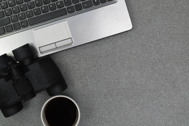 istock Laptop computer or notebook, binocular and cup of coffee on working table with copy space top view. 869926508