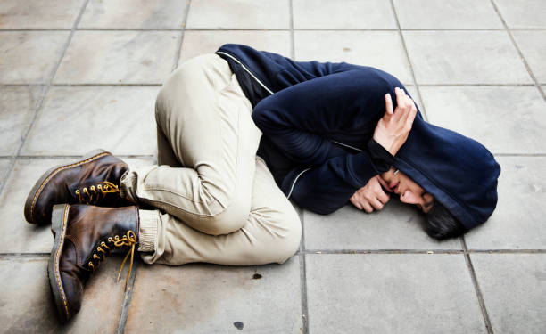 istock Guy in a hoodie fetal position on the floor 869940182