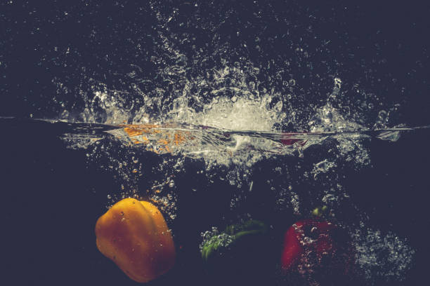 istock Green Yellow Red bell peppers drop into the water with splash. 869950600
