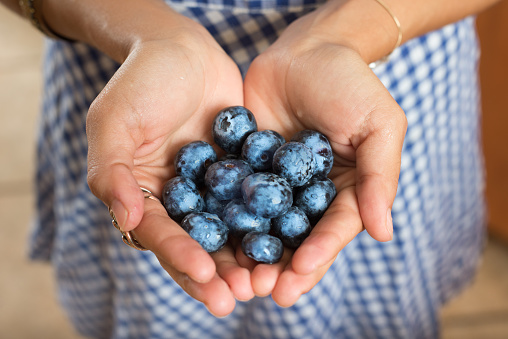 Hispanic Women In The Kitchen Holding Blueberries