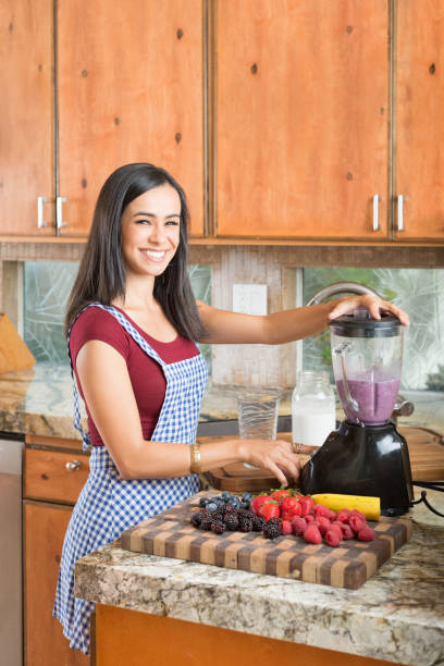 istock Hispanic Women In The Kitchen Making A Smoothie 869956472