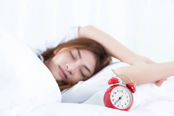 istock woman waking up and turning off the alarm clock 869970238