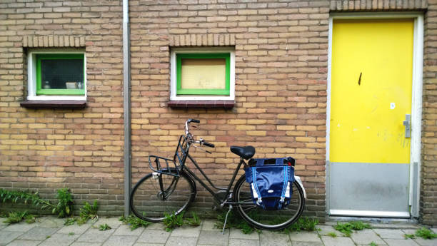 The usual Amsterdam entrance in a residential house, near a parked bike. Bright yellow front door stock photo