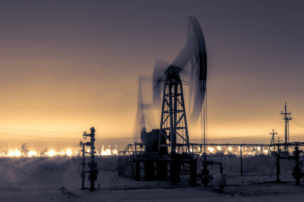 istock Pump jack and refinery at night. 869991860