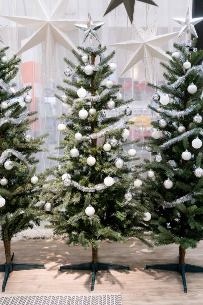 istock White and silver decorative Christmas tree with tinsel garland, glitter balls, and silver star for interior seasonal greeting. 869992076