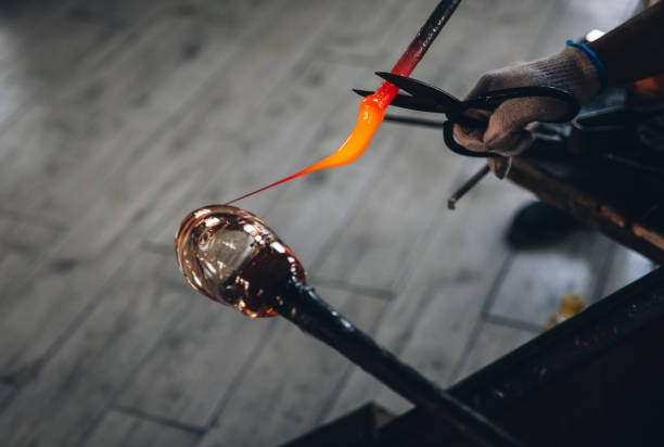 istock Traditional glassblowing worker cutting liquid glass 869996270