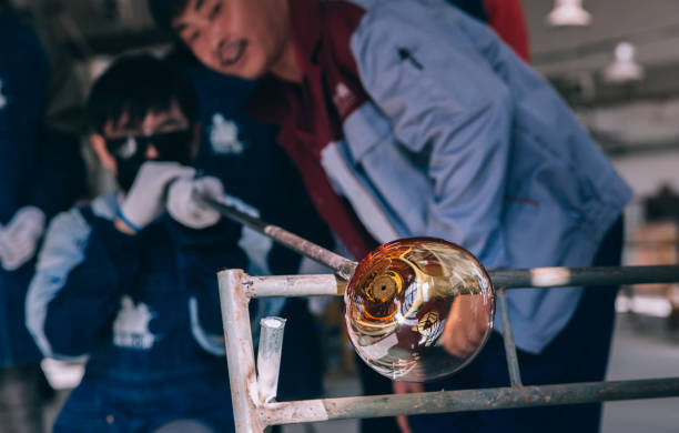 The Details and Close-up of a worker blowing glass at a glass factory.