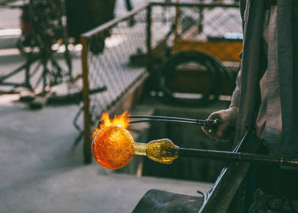 istock Traditional glassblowing worker heating liquid glass 869996522