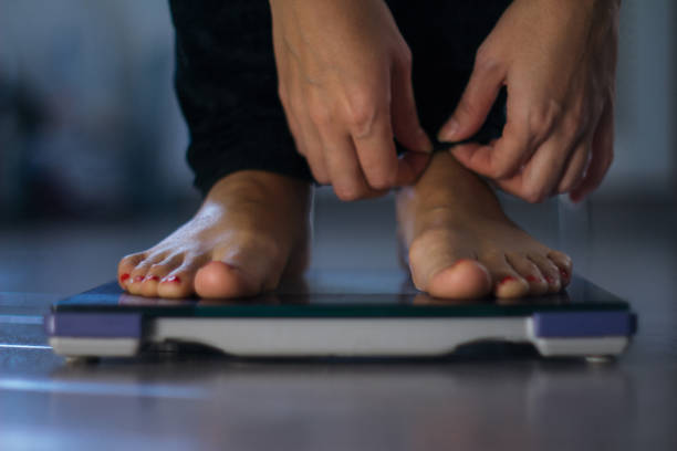 istock Female measuring weight on health scale 869999456