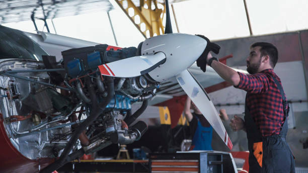 Man cleaning aircraft propeller in hangar