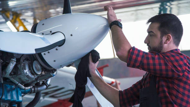 istock Man cleaning aircraft propeller in hangar 870008894