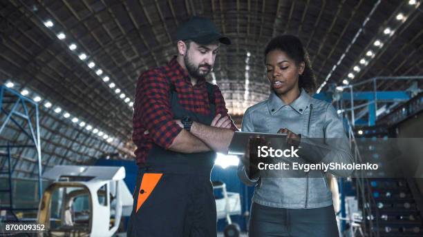 Man Discussing In Aircraft Hangar With Woman Stock Photo - Download Image Now - Air Vehicle, Airplane Hangar, Engineer