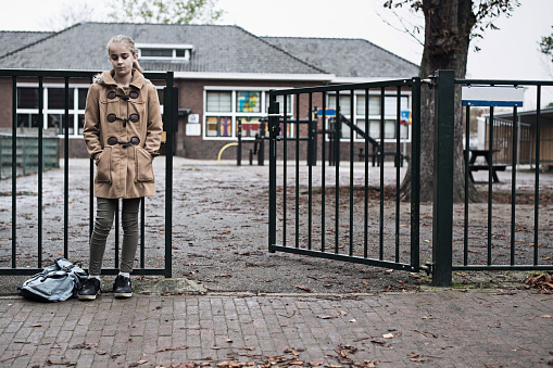 Schoolgirl at school outside sad and alone. Concept of bullying or insecurity