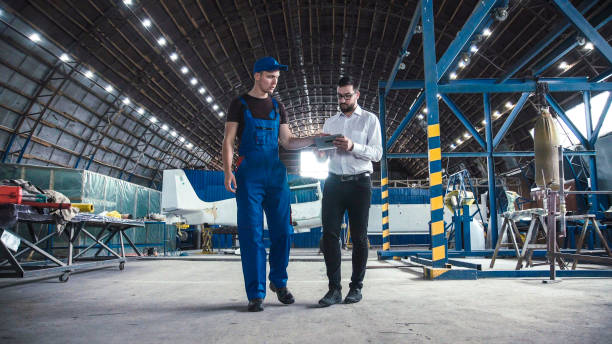 Mechanic and flight engineer having a discussion Mechanic and flight engineer having a discussion together as they stand in aircraft in a hangar. airplane maintenance stock pictures, royalty-free photos & images