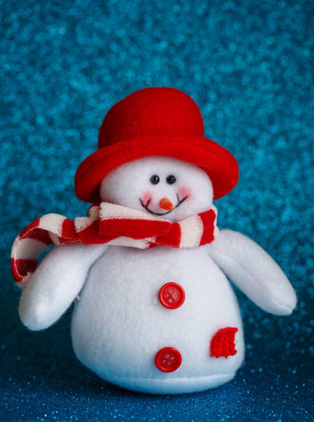 istock Smiling snowman toy dressed in scarf and cap on abstract bokeh background. 870012084