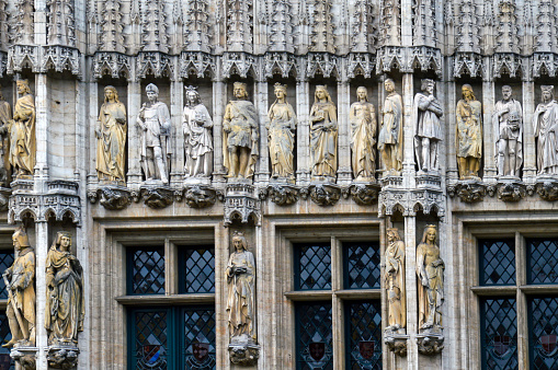 The facade of the Town Hall of the City of Brussels, a building of gothic architectural style from the middle ages decorated with numerous statues representing nobles, saints, and allegorical figures, located at the Grand Place in Brussels, Belgium