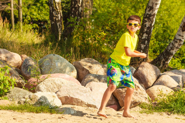 Play and fun concept. Little playful enjoyable boy kid throwing frisbee disc. Male child having fun playing outdoor on beach.