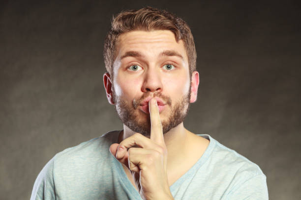 istock Man with finger on lips showing silence gesture. 870023684