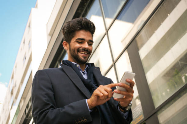 istock Smiley business man on street typing on mobile. 870023690