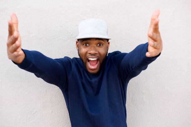 istock excited young african man with arms outstretched and laughing 870026246