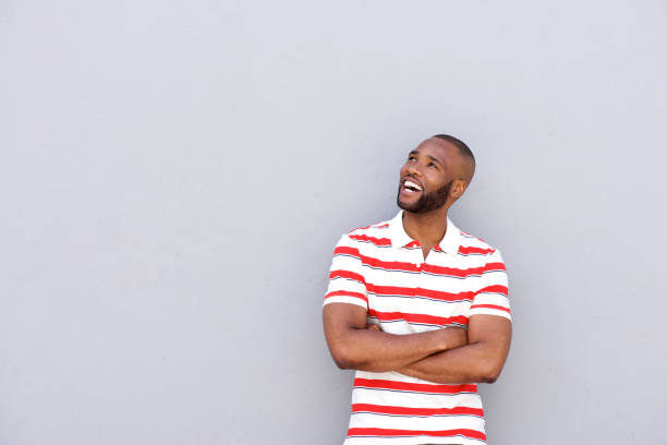 istock cool african man smiling against gray wall looking at copy space 870026392