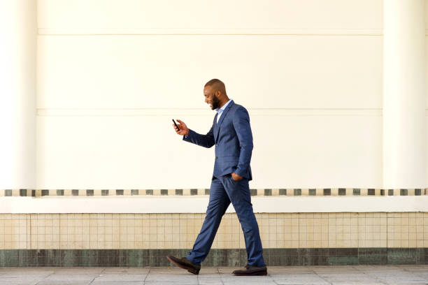 istock young businessman walking outdoors and using cell phone 870026462