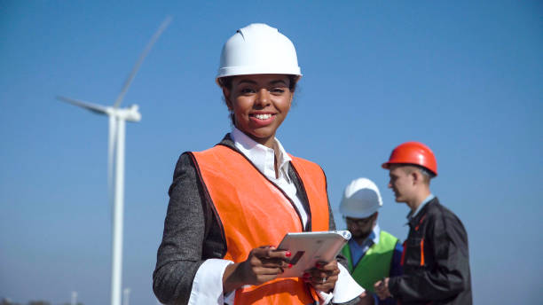istock Woman with protective helmet against wind turbine 870029994