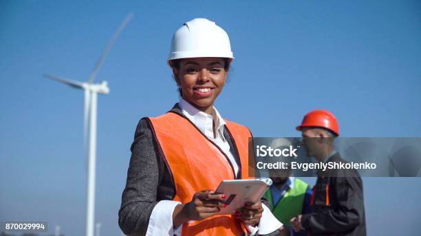 Woman With Protective Helmet Against Wind Turbine Stock Photo - Download Image Now - Engineer, Women, Occupation