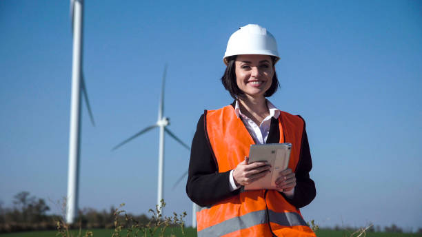 istock Smiling female engineer standing against wind farm 870030376