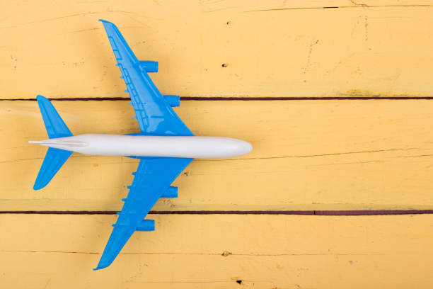 istock Toy plane on yellow wooden background. Top view 870030724