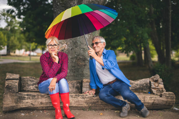 personnes aînées avec parapluie en automne pluvieux - umbrella senior adult couple autumn photos et images de collection