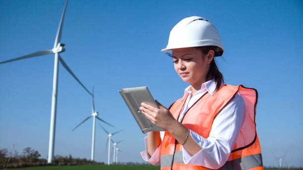 istock Woman with hard hat against wind turbine 870030866