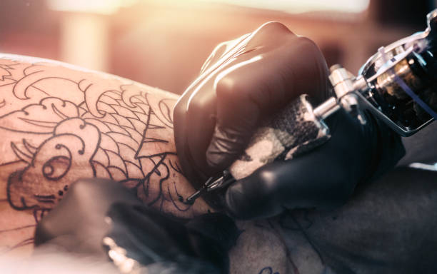 istock Tattoo master making tattoo on customer's leg 870032134