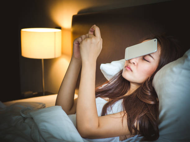 sueño mujer asiática en la cama blanca, cayó teléfono inteligente en la cara - pillow wake up yawning sleeping fotografías e imágenes de stock
