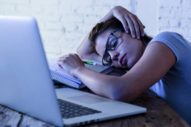 istock young beautiful and tired student girl sleeping taking a nap lying on home laptop computer desk exhausted and wasted spending night studying in stress preparing exam 870056558