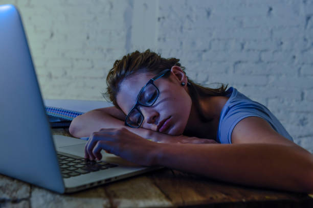 istock young beautiful and tired student girl sleeping taking a nap lying on home laptop computer desk exhausted and wasted spending night studying in stress preparing exam 870056580