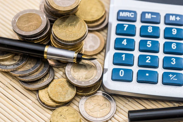 istock Euro coin with pen and calculator. close up. 870057368