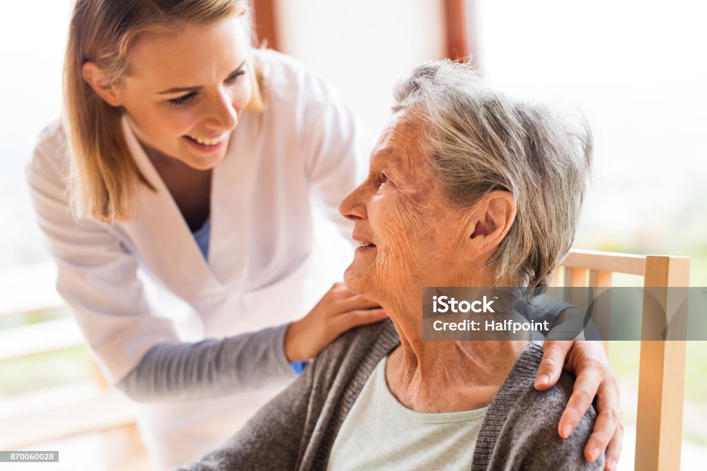 Visitatore della salute e una donna anziana durante la visita a casa. - Foto stock royalty-free di Terza età