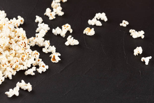 istock Popcorn horizontal banner. Red stripped paper cup and kernels lying on dark background. Copy space. 870064074