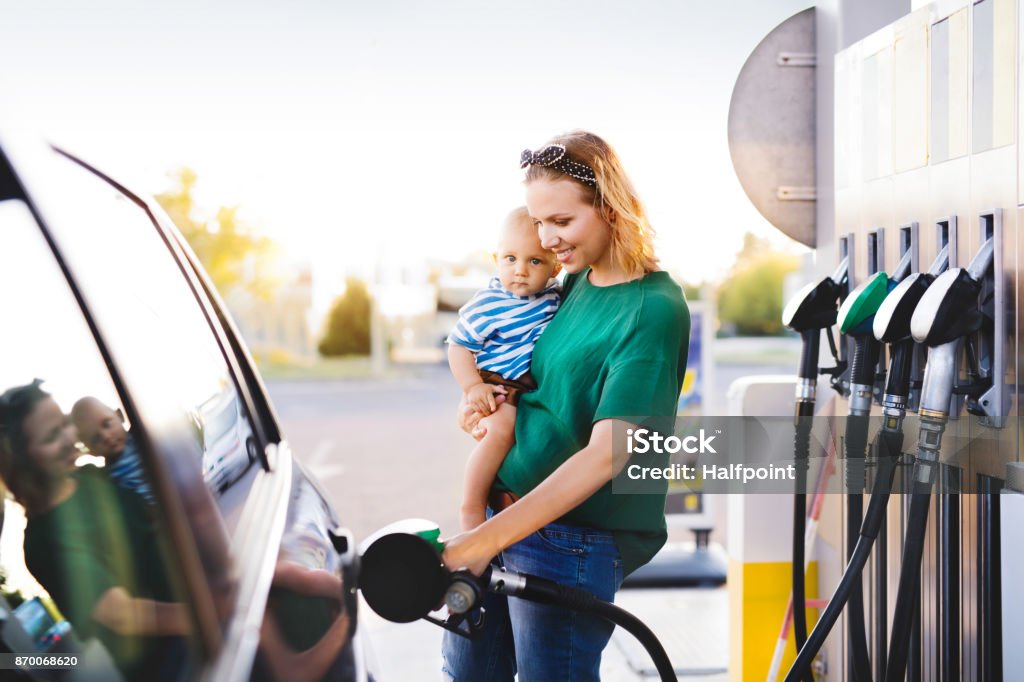 Young mother with baby boy at the petrol station. Young mother with baby boy at the petrol station refuelling the car. Refueling Stock Photo