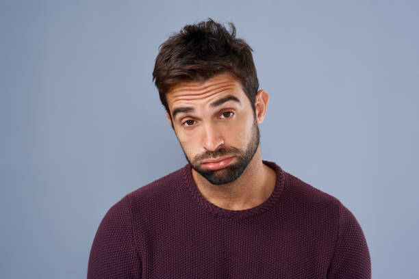 I need an emotional boost Studio shot of a handsome young man looking sad against a gray background sulking stock pictures, royalty-free photos & images
