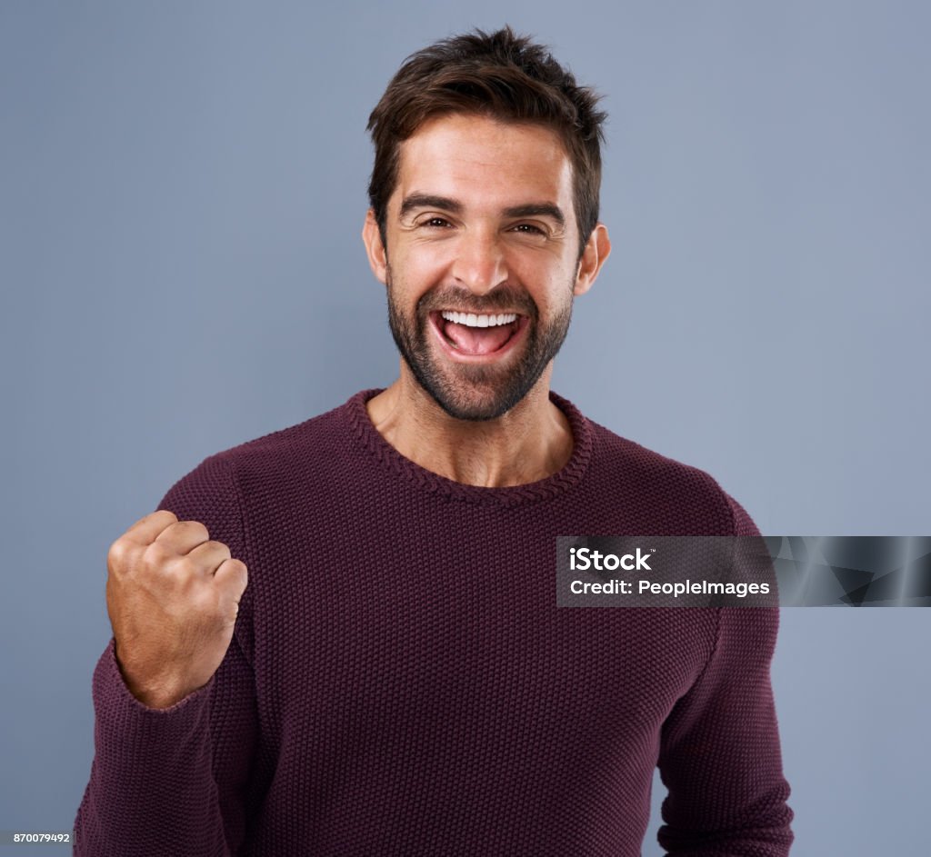 Nothing feels as good as winning! Studio shot of a handsome young man cheering against a gray background Men Stock Photo
