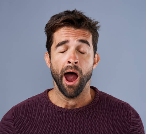 Is this day over yet? Studio shot of a handsome young man yawning against a gray background yawning stock pictures, royalty-free photos & images