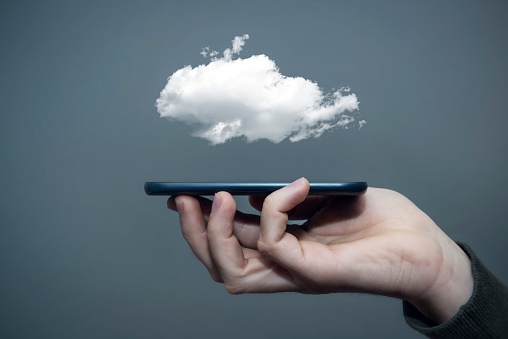 cloud storage concept photo. mobile phone in the hand with cloud over it.