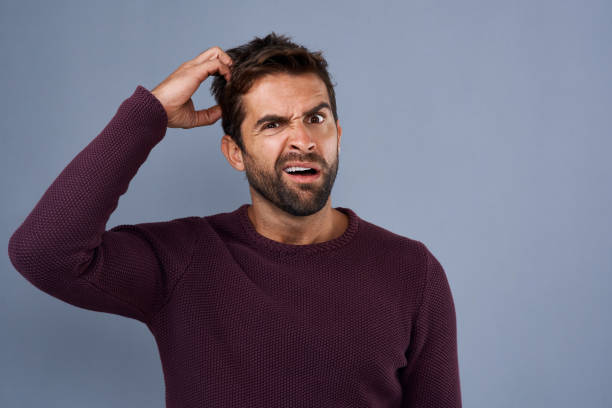 Huh? I don't get it Studio shot of a young man scratching his head in confusion against a gray background fool photos stock pictures, royalty-free photos & images