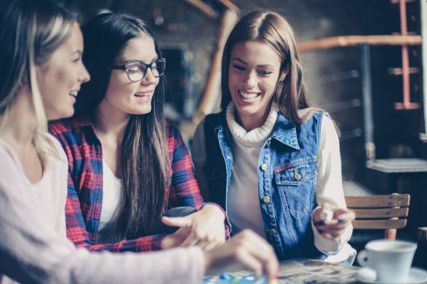 istock Three cheerful  girls playing board game. 870083670