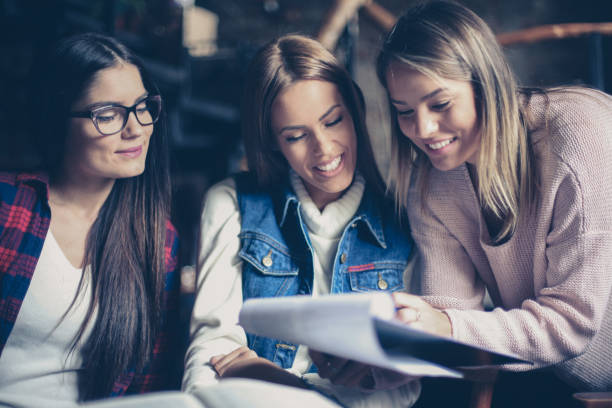 Three students girl reading file together indoors. Close up. Three students girl reading file together indoors. Close up. dealing room photos stock pictures, royalty-free photos & images