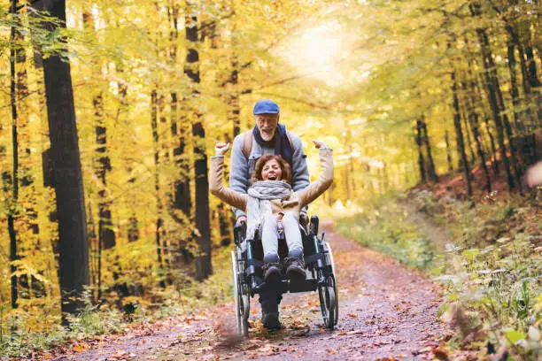 Photo of Senior couple with wheelchair in autumn forest.